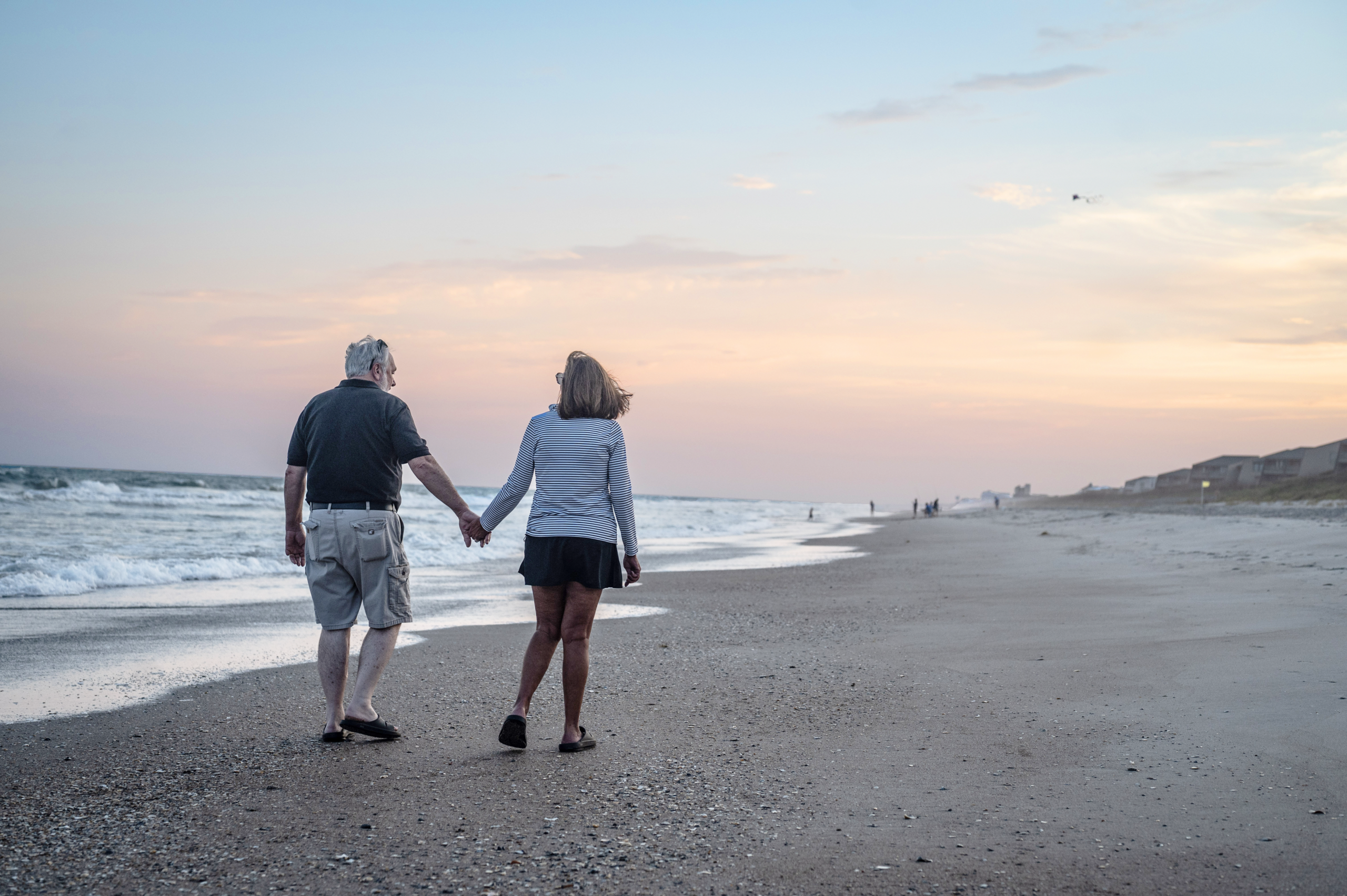 Couple walking on the beach as the sun set in the background