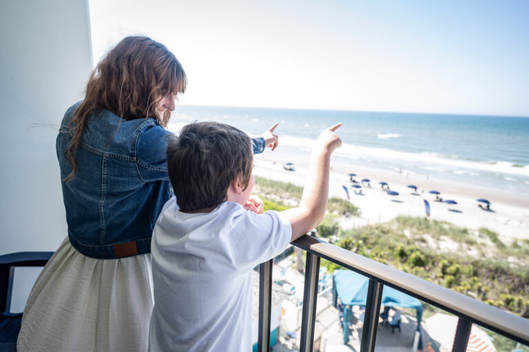 Mom and son on balcony at Crystal Coast Oceanfront Hotel